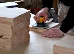 man sanding wood with a small orbital sander