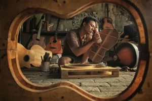 man gluing guitar in a shop